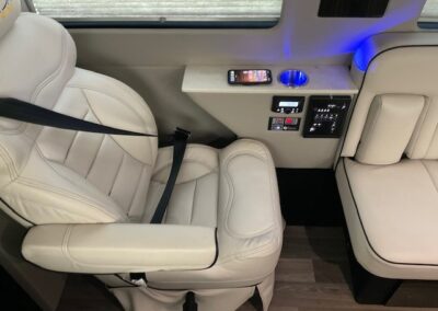 Interior of indulger specialty vehicle showing white seat and electronic display with shelf holding phone and cupholder.