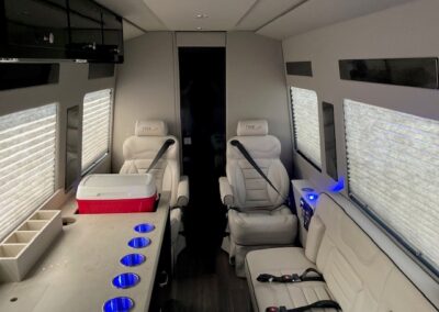 Interior of indulger specialty vehicle showing countertops, cooler, bench seat, and 2 white bucket seats.