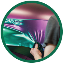 Round image of person wrapping specialty vehicle.