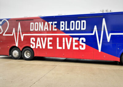 Side view of exterior of mobile blood specialty vehicle that says "Donate Blood Save Lives"