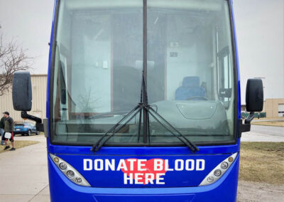 Front end view of exterior of blood mobile specialty vehicle that says "Donate Blood Here"