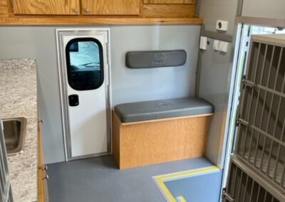 Interior view of Augusta Pet Adoption specialty vehicle showing bench seat, small door, upper cabinets, countertop with sink, and cages for animals.