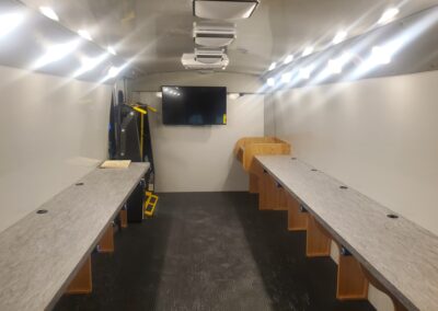 Interior view of tables on each side and tv in back of educational mobile classroom specialty vehicle.