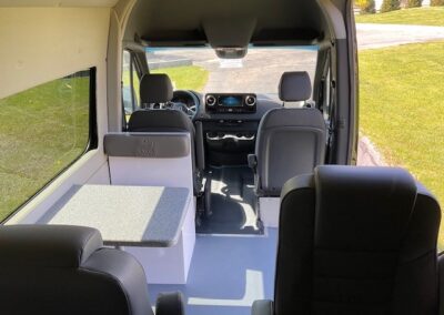 Interior image of Mobile Marketing specialty vehicle. Shows 3 seats in the back, a small table on the left, and two seats in the front.