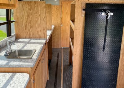 Interior of an Outreach Mobile Meal Dispensing specialty vehicle. Image shows sink, countertops, and cabinets on the left, shelves on the right.