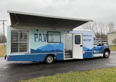 Outside of P.A.W.S mobile pet services vehicle with awning out