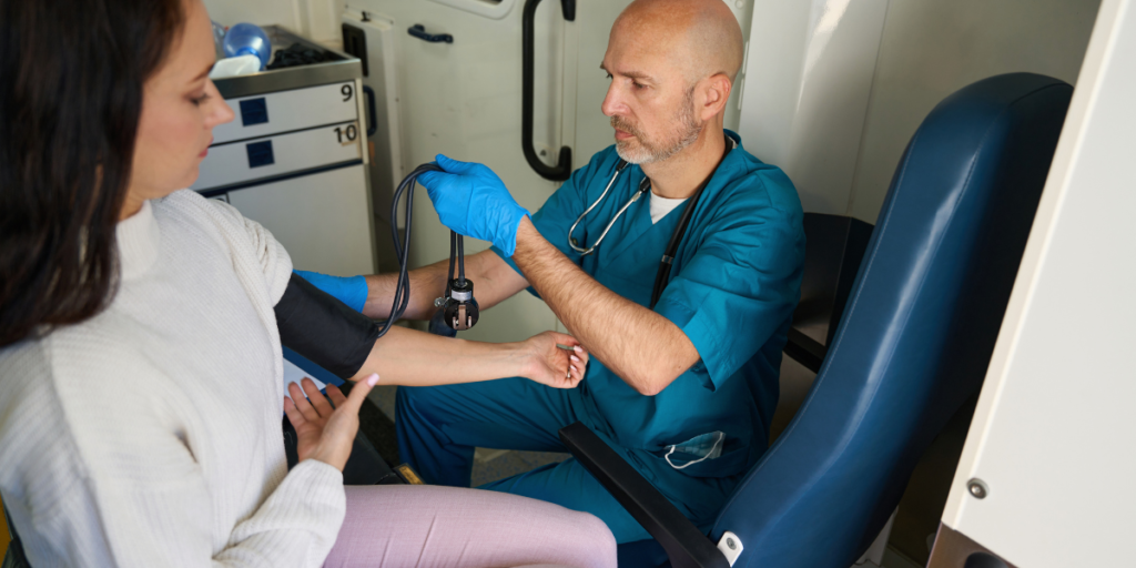 doctor in mobile healthcare unit taking woman's blood pressure