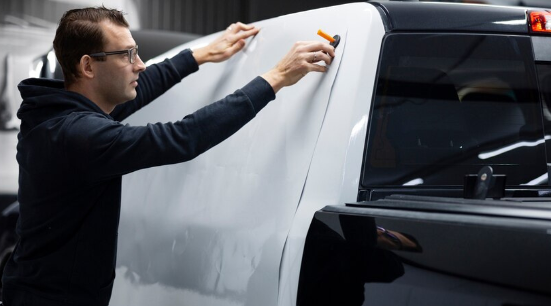 A vehicle upfitting expert wrapping a vehicle.