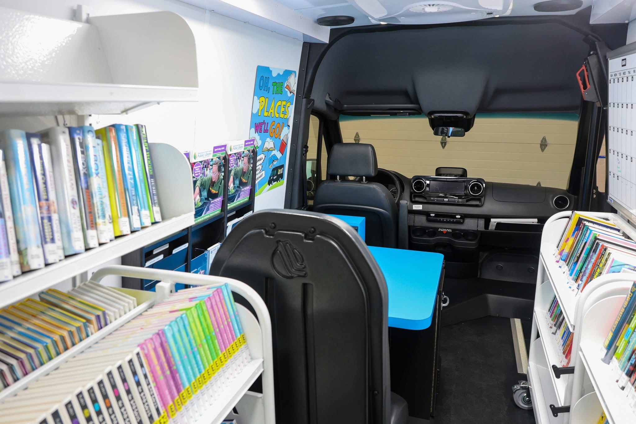Interior image of Bookmobile specialty vehicle showing blue bookshelves on each side.